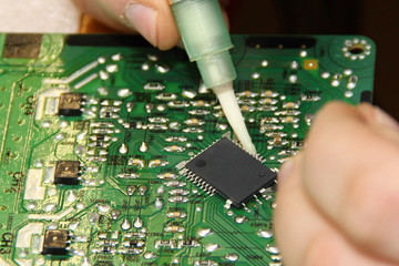 Digital electronics repair, applying flux solder from a syringe to the processor contacts for...