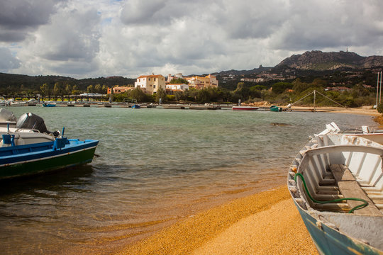 A view towards Cala Volpe, beutiful sandy beach with boats on the shore. Houses in the background.