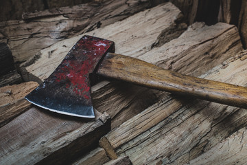 Hatchet axe lying on a pile of split wood logs used for fire. Concept of making logs portrayed in natural colors- Axe viewed from the top side with a shiny sharp blade.
