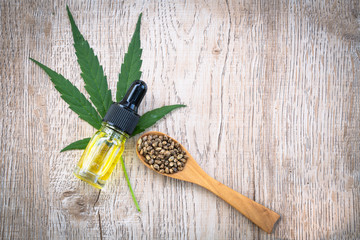 Hemp seeds and hemp oil on brown wooden table. CBD hemp oil.