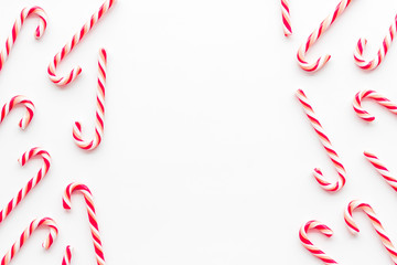 Christmas candies frame - cane with red and white stripes - on white background top-down copy space