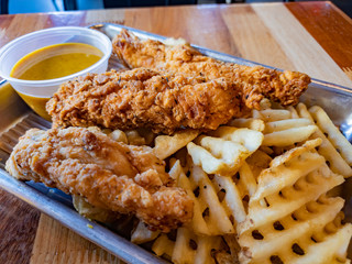 Close up shot of a plate of deep fried chicken breast and potato slice
