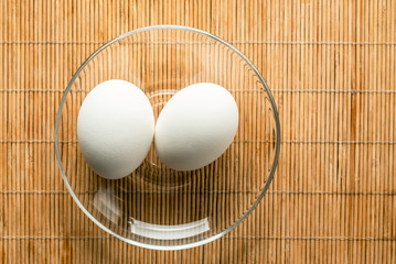 Chicken eggs in saucer on a bamboo background