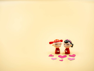 Chinese marriage couple dolls wear red ancient gown and groom clothing with pink heart stickers and gold colored background for wedding, love, valentines day concepts and ideas.