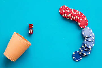 Poker hazard game concept. Chips, dices, cup for dice on blue background top-down copy space