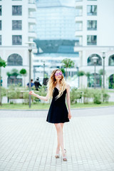 Obraz premium A beautiful girl of doll appearance in a black dress on a city street. Natural sunlight
