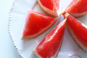 Fototapeta na wymiar Cut fruit, red ruby grapefruit on dish for healthy dessert