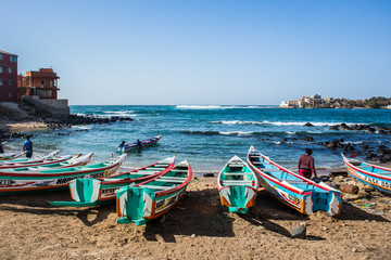 Fishing boats in Ngor Dakar, Senegal, called pirogue or piragua or piraga. Colorful boats used by fishermen standing in the bay of Ngor on a sunny day. - obrazy, fototapety, plakaty