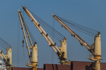 A set of white cranes or elevators mounted on a cargo ship.