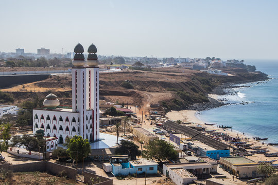 Mosque of divinity or mosquee de la divinite in Dakar, Senegal, behind a signboard leading towards the mosque on a sunny day. City of Dakar in the background.