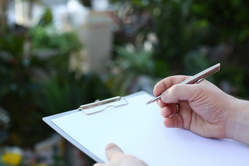 Human Hand Writing on Clipboard with White Paper