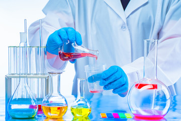 Laboratory assistant conducts experiments with chemical liquids. The man mixes the substances....