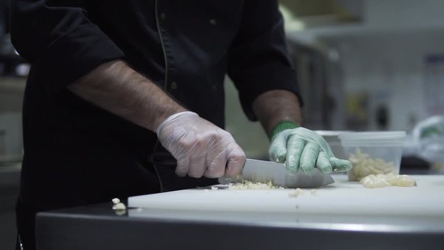 Mincing garlic to deep dry and used as a topping for a dish. This was taken at a higher frame rate and has been converted to a slow motion video clip.