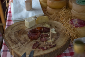 Detailed view of a hand slicing homemade pork chorizo and cheese on wooden table