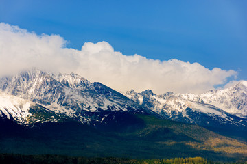 high tatras mountain ridge in springtime. snow capped rocky peaks in dramatic dappled sunlight...