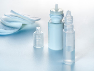 On a horizontal white background are bottles with eye drops and cotton pads.