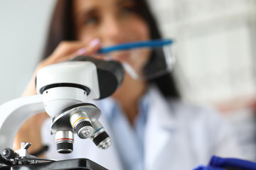 Scientific microscope lens with female analyst in background