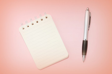 Lined notebook and pen on a pink background close-up. Top view, copy space. Education concept retro style toned