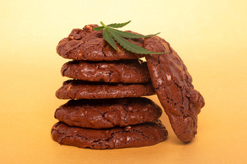 cannabis cookies and green leaf. chocolate peanut cookies with marijuana oil on a yellow background.