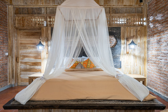 Comfort bedroom with mosquito net and night lamps over bedside table