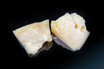 Broken pieces of hard cheese on dark surface, top view