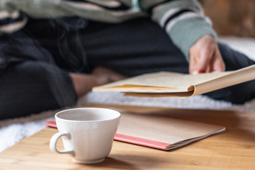 Girl working at home with notebooks and sitting on the floor with a hot drink.