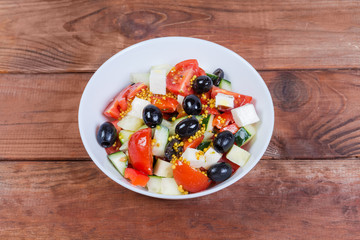 Vegetable salad with soft cheese in bowl on rustic table