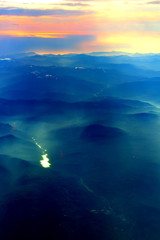 Obraz premium spectacular sunset seen from an airplane with the sun reflecting off a river and the mountains in the background