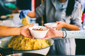 The poor reach out to receive donated food: Homeless people receive free charity food.