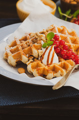 Belgian waffles with cream and red currant, nuts for breakfast.