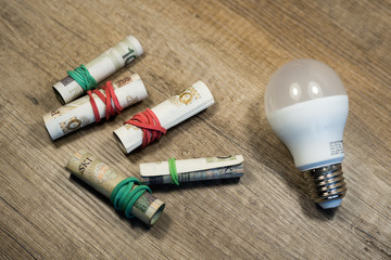 Naklejka premium Money rolled up with an elastic band with bulb on wooden table. Polish currency. Polish zloty banknotes. Polish money. PLN