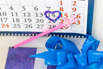 desk calendar, pink pencil. 14 circled in red in the shape of a heart. Have a gift box.