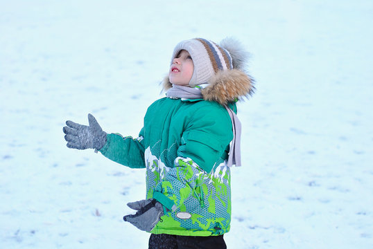 Happy Kid Playing Outside With Snow. Snowed Winter Time Season, Frost And Cold Weather. Children Dressed Up In Warm Clothes Cap With Pompon And Light Green Jacket With Fluffy Hood. Healthy Kids Walk