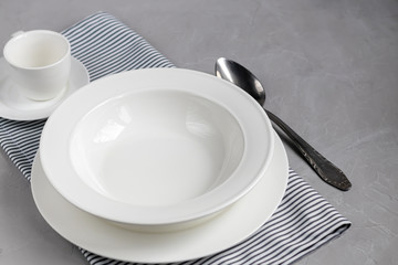 Dining layout. Beautiful serving on a gray linen napkin. A plate for soup or a side dish. Light gray background and white plates.