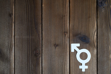 male and female symbol for gender equality cut out of paper on a wooden background. space for text