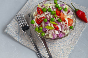 Diet salad made from fresh vegetables. Peking cabbage lilac and green, tomatoes, green onions and chili peppers. Dressed with olive oil.