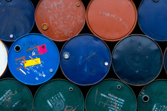 Old chemical barrels. Blue, green, orange oil drum. Steel oil tank. Toxic waste warehouse. Hazard chemical barrel with warning label. Industrial waste in metal drum. Hazard waste storage in factory.