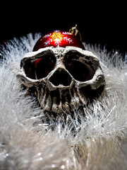 front view of menacing white human skull with the christmas ball and christmas decoration on a black background close-up.