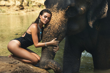 Happy woman is bathing with the elephant in the river