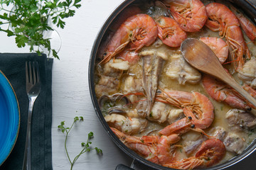 Typical Spanish fish Zarzuela served on a wooden table. Mediterranean travel cuisine with empty...