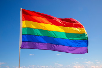 Rainbow gay pride flag against blue sky