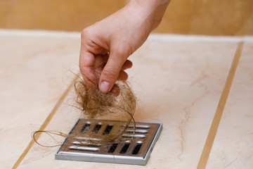 Woman removing hair clump from the shower drain