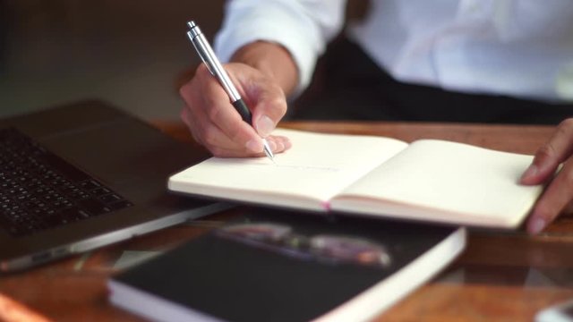 4k video of man hand holding pen writing to do list or business data  with pen at notebook dairy