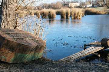 View of a frozen lake with smooth ice. On the shore of an inverted boat