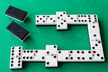 Top view of domino game with unfocused chips in the background on green mat horizontal