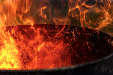 Close-up of red, yellow and orange flames in a blackened old metal bin
