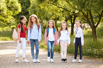 Obraz premium School kids stand embracing in a row outdoors, full length