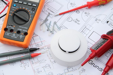 smoke detector with a screwdriver and a measuring device on a circuit diagram