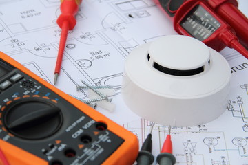 smoke detector with a screwdriver and a measuring device on a circuit diagram