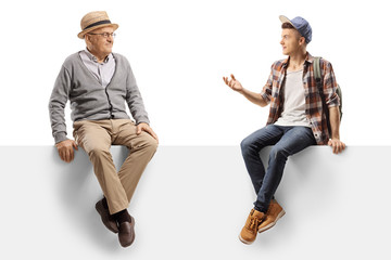 Elderly man and a teenager sitting on a panel and talking